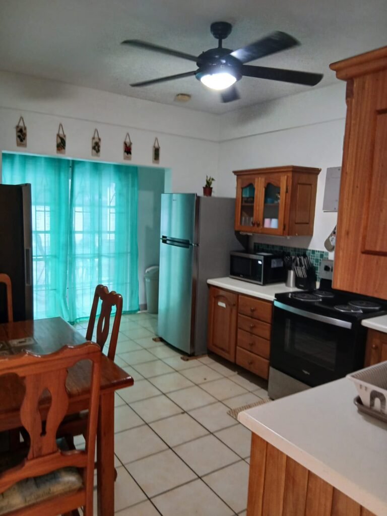 Bona Villa, Bon Accord, Tobago: the kitchen seen from the dining table, with the cooker and fridge beyond.